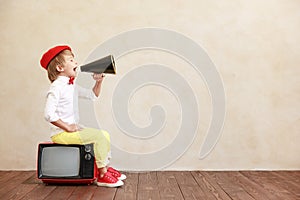 Newsboy shouting against grunge wall background. Boy selling newspaper