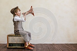 Newsboy shouting against grunge wall background. Boy selling newspaper