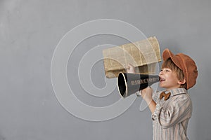 Newsboy shouting against grunge wall background. Boy selling newspaper