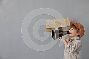 Newsboy shouting against grunge wall background. Boy selling newspaper
