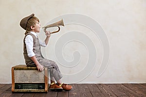 Newsboy shouting against grunge wall background. Boy selling newspaper