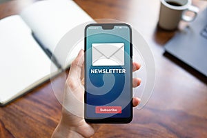 Newsletter subscription button on mobile phone screen. Business marketing concept.