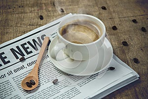 A newspaper and a cup of coffee on a wooden table