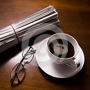 Newspaper, glasses and cup on desk