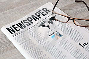 Newspaper with glasses on wooden background