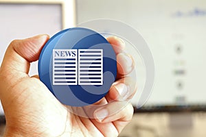 Newspaper icon blue round button holding by hand infront of workspace background