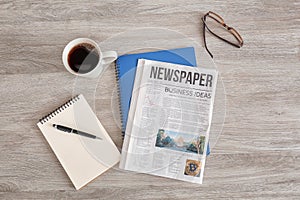 Newspaper, notebooks and cup of coffee on wooden table