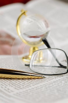 Newspaper, pen, glasses and globe