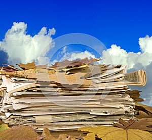 Newspapers and autumn leaves against the sky