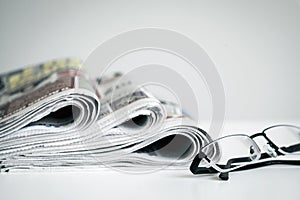 Newspapers with eyeglasses on white background