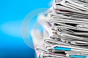 Newspapers folded and stacked on the table with blue background.Closeup newspaper and selective focus image.Time to read concept