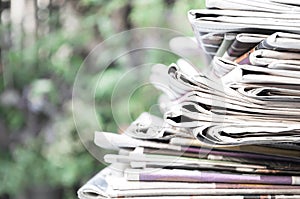 Newspapers folded and stacked on the table with garden. Closeup newspaper and selective focus image.Time to read concept