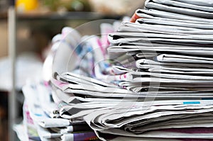 Newspapers folded and stacked on the table with outdoor garden or bright color background. Closeup newspaper and selective focus i