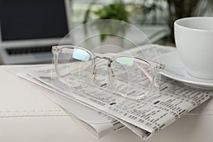 Newspapers, glasses and cup of drink on armrest indoors