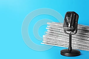 Newspapers and vintage microphone on blue background, space for text. Journalist`s work