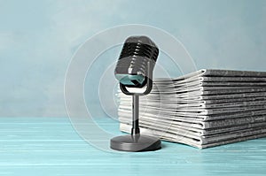 Newspapers and vintage microphone on blue wooden table. Journalist`s work