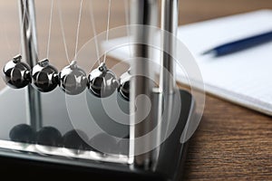 Newton`s cradle on wooden table, closeup. Physics law of energy conservation