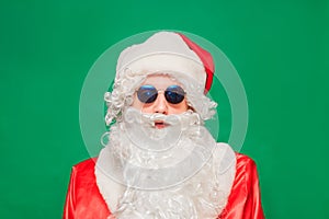 Newyear atmosphere presents, wear red santa costume sunglass headwear. isolated green color background