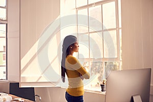 The next gap in the market is out there. a young businesswoman looking thoughtfully out of a window in a modern office.