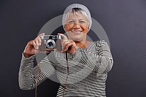 The next great photographer. Portrait of a mature woman holding a camera in a studio.