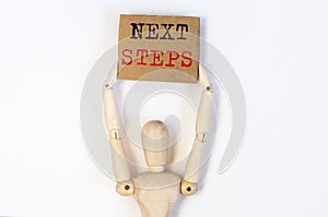 Next steps phrase on craft paper in wooden person hands, planning concept