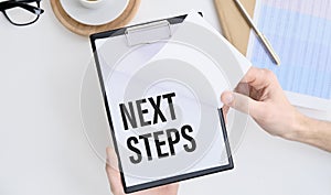 NEXT STEPS text on wooden desk with tablet pc