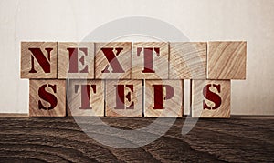 Next Steps written on a wooden cubes in a office desk. Education and business startup concept