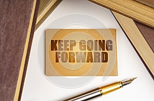 Next to the books lies a pen and a sign with the inscription - Keep Going Forward