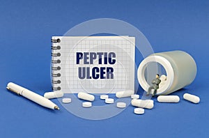 Next to a jar of pills and a figurine of a man, a notepad with the inscription - Peptic ulcer