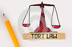 Next to the painted scales of justice lies a pencil and a strip of paper with the inscription - Tort Law