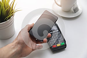 Nfc contactless payments - hand holding phone above payment terminal