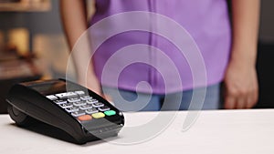 NFC technology. Close-up of young caucasian woman using credit card with NFC chip on bank terminal. Customer paying for