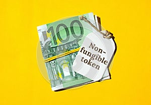 NFT non-fungible token text. Concept words NFT non-fungible token on paper blank. Background of euro bills. Blockchain photo