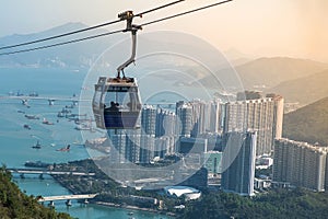 Ngong Ping Cable car with tourists over harbor, mountains and city background, to visit the Tian Tan or the Big Buddha located at