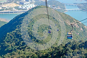 Ngong Ping Cable car with tourists over harbor, mountains and city background, to visit the Tian Tan or the Big Buddha located at