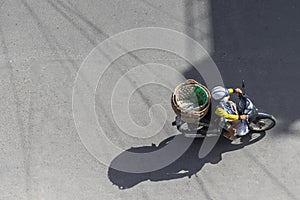 Nha Trang, Vietnam - January 7, 2019: A woman rides a motorbike with empty baskets on the asphalt