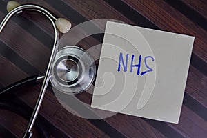 NHS write on sticky notes isolated on Wooden Table photo