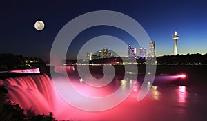 Niagara Falls at dusk including the moon and skyline of the Canadian city on the background