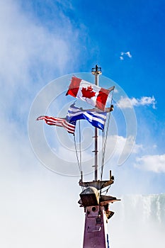 Niagara Falls, on the famous Falls boat tour, the canadian and american flag flying on the mast of Niagara Cruise Boat