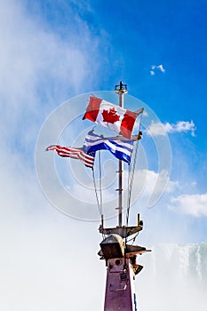 Niagara Falls, on the famous Falls boat tour, the Canadian and American flag flying on the mast of Niagara Cruise Boat