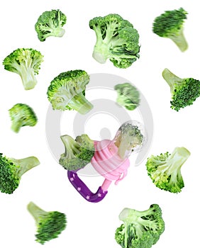 Nibbler and  green broccoli falling on white background. Baby feeder photo