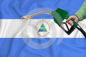 NICARAGUA flag Close-up shot on waving background texture with Fuel pump nozzle in hand. The concept of design solutions. 3d