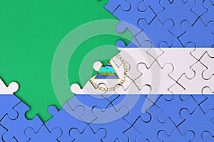 Nicaragua flag is depicted on a completed jigsaw puzzle with free green copy space on the left side