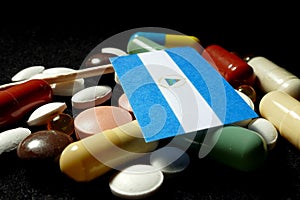 Nicaraguan flag with lot of medical pills isolated on black back