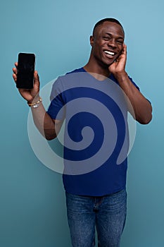 nice 25s african guy in casual blue t-shirt showing smartphone screen