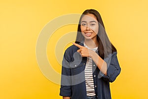 Nice advertisement! Portrait of happy pretty girl in denim shirt pointing to side copy space, gesturing attention