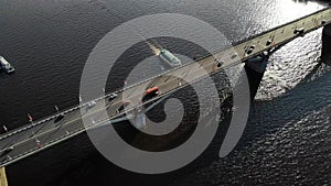 Nice aerial footage of a bridge with cars and busses with ship going down the river under bridge.