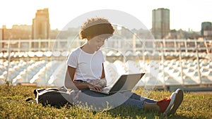 Nice african american female student typing on laptop pc outdoors, freelance