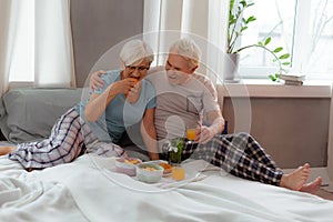 Nice-appealing wife eating croissant while her husband is cuddling her