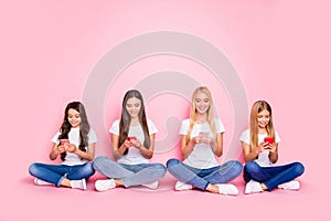 Nice attractive cheerful cheery focused girls sitting on floor crossed legs chatting using 5g app browsing web internet